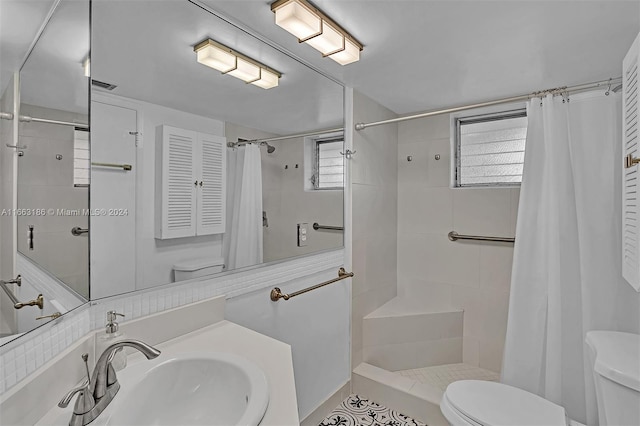 bathroom featuring walk in shower, sink, toilet, and a healthy amount of sunlight