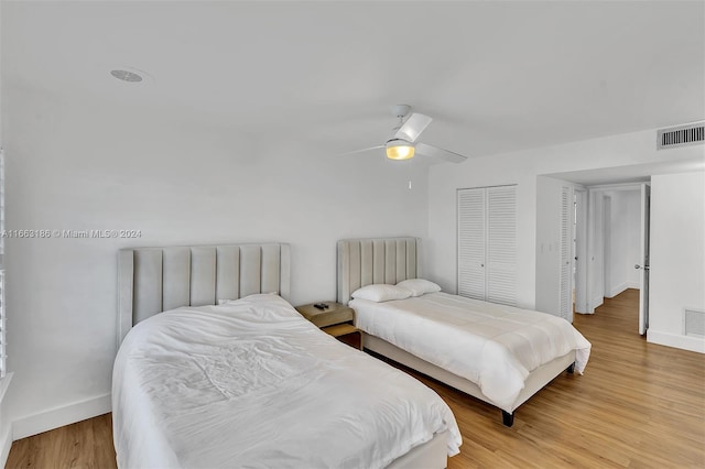 bedroom with light hardwood / wood-style flooring, multiple closets, and ceiling fan