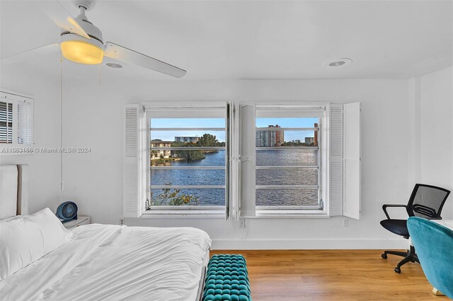 bedroom with a water view, ceiling fan, and hardwood / wood-style floors