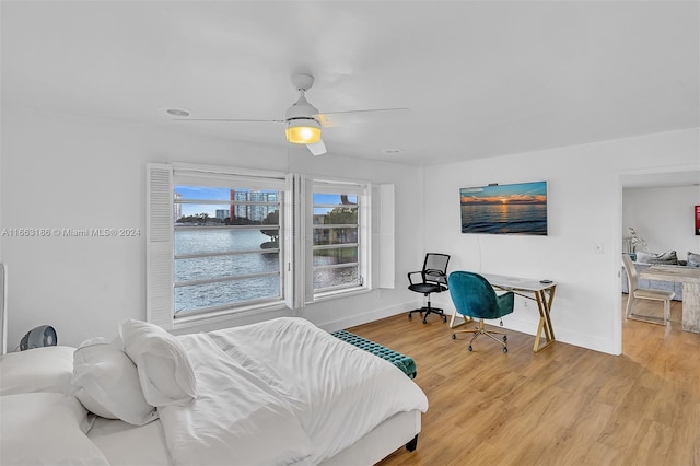 bedroom featuring a water view, ceiling fan, and hardwood / wood-style floors