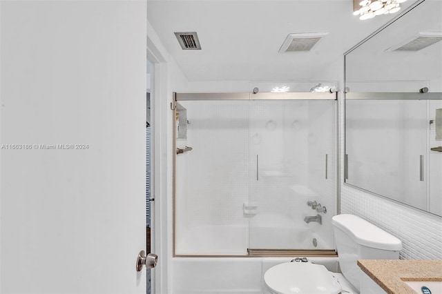 full bathroom featuring combined bath / shower with glass door, vanity, and toilet