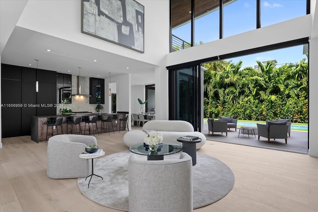 living room with light wood-type flooring and a towering ceiling