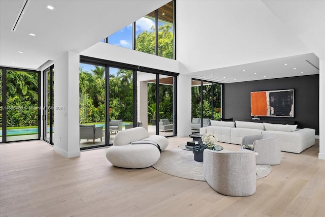 living room featuring a towering ceiling, light hardwood / wood-style floors, and expansive windows