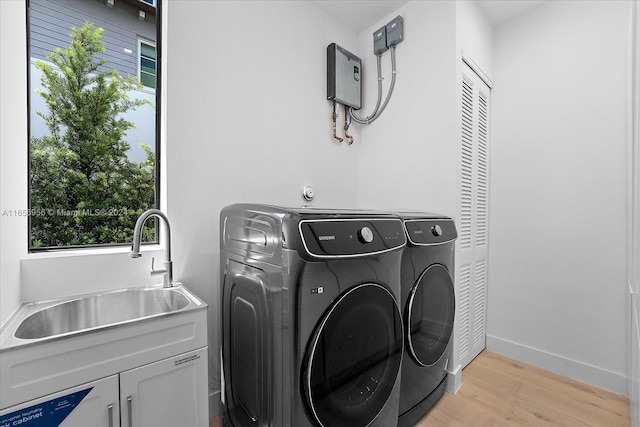 laundry room with cabinets, light hardwood / wood-style flooring, sink, and a wealth of natural light