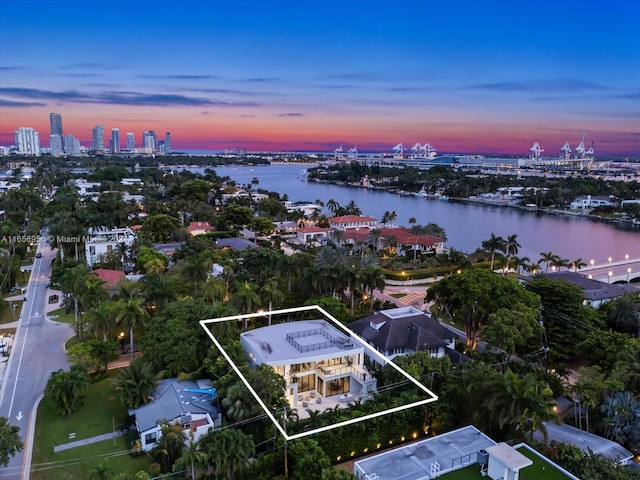 aerial view at dusk featuring a water view