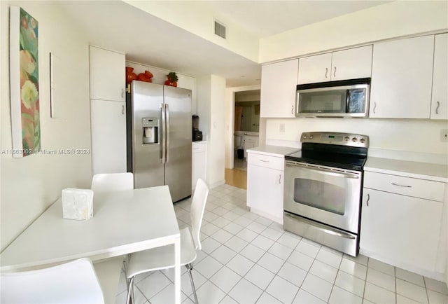 kitchen featuring stainless steel appliances, white cabinets, and light tile patterned floors