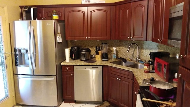 kitchen featuring light stone countertops, appliances with stainless steel finishes, sink, and decorative backsplash