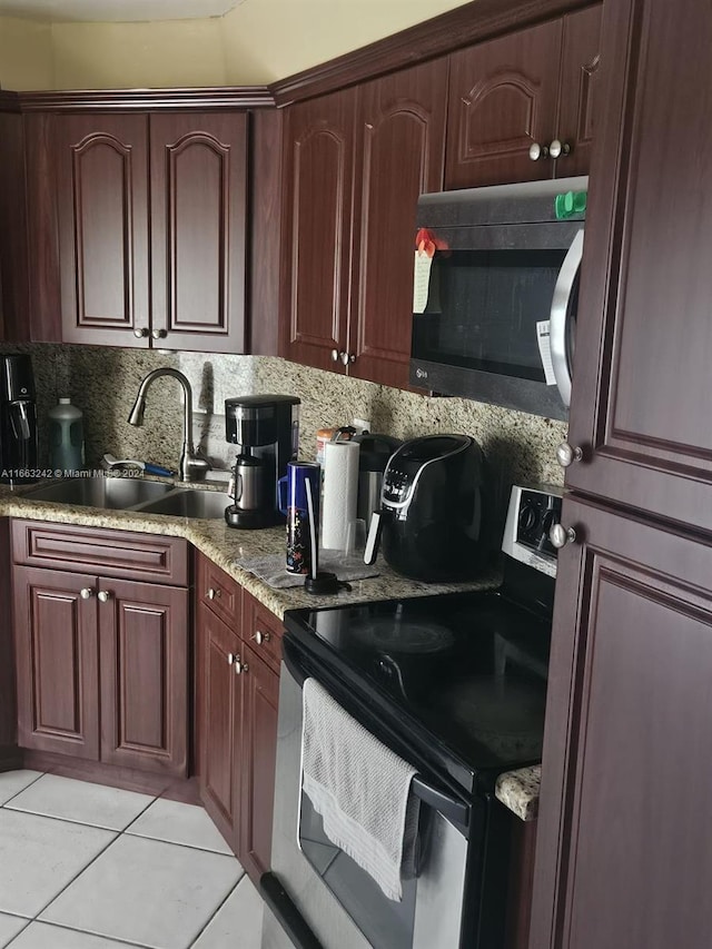 kitchen with light tile patterned floors, sink, appliances with stainless steel finishes, light stone countertops, and decorative backsplash