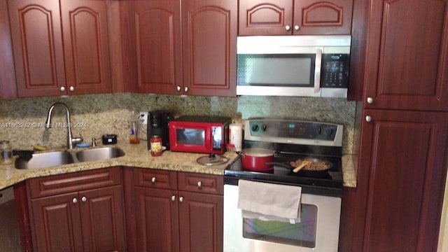 kitchen with light stone counters, appliances with stainless steel finishes, sink, and decorative backsplash