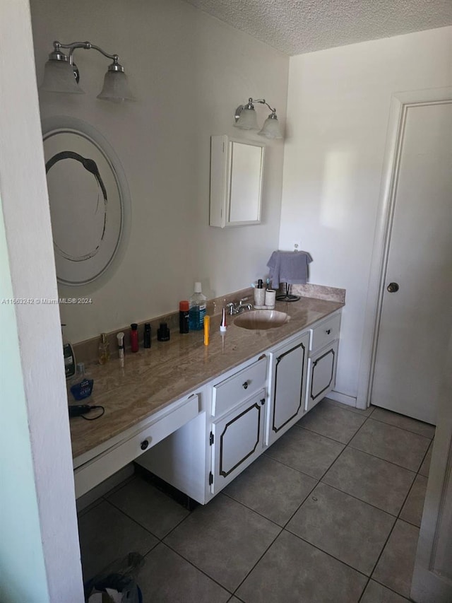 bathroom with a textured ceiling, tile patterned flooring, and vanity