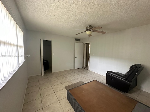 unfurnished living room with a textured ceiling, light tile patterned floors, and ceiling fan