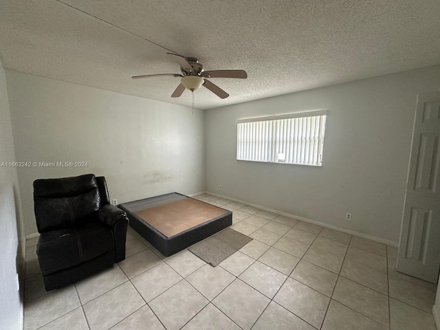 sitting room with ceiling fan, light tile patterned floors, and a textured ceiling