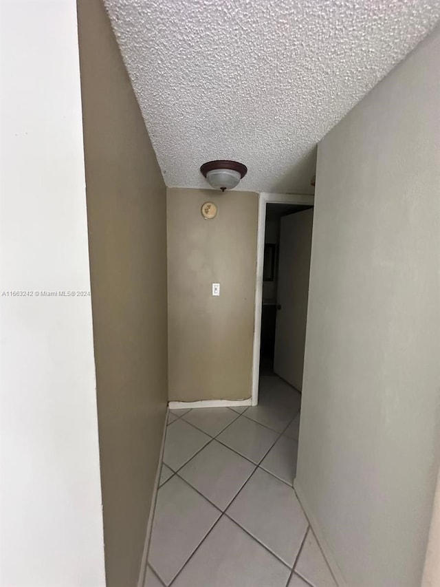 corridor featuring a textured ceiling and light tile patterned floors