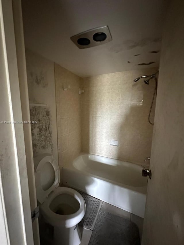 bathroom with tiled shower / bath combo, tile patterned flooring, and toilet