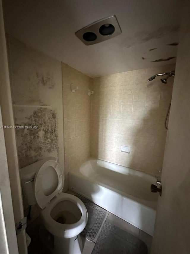 bathroom featuring tiled shower / bath combo, toilet, and tile patterned floors