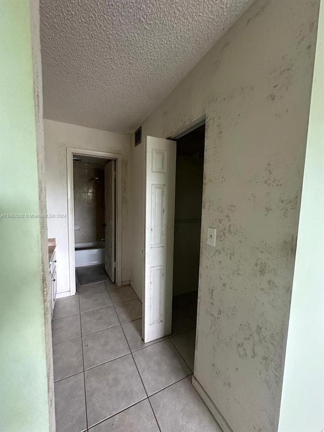 hallway featuring a textured ceiling and light tile patterned flooring