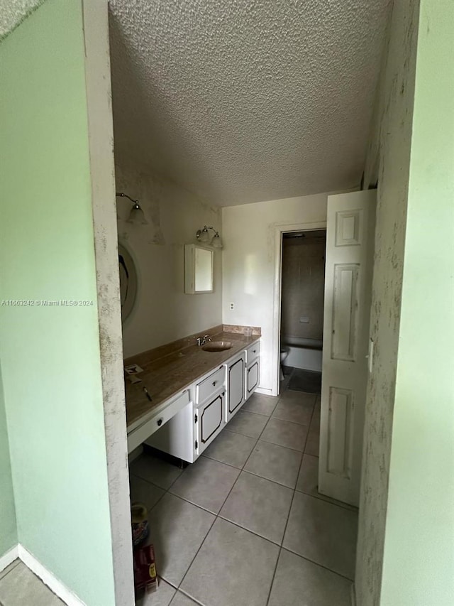 bathroom with a textured ceiling, tile patterned flooring, vanity, and toilet