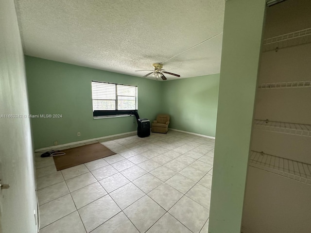 tiled empty room with a textured ceiling and ceiling fan