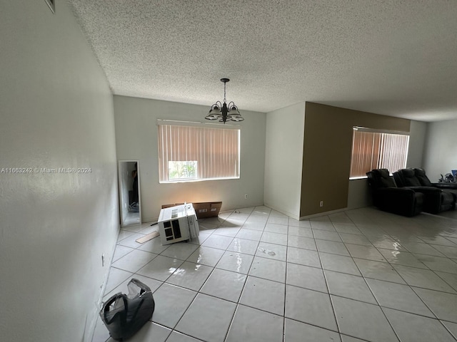 interior space with a textured ceiling, a notable chandelier, and light tile patterned flooring