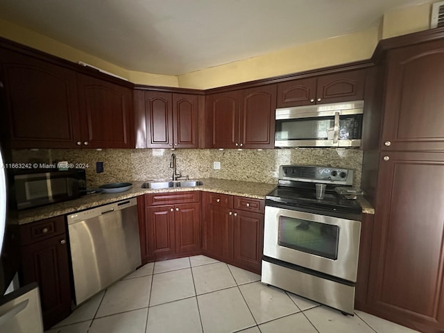 kitchen with appliances with stainless steel finishes, light tile patterned flooring, tasteful backsplash, light stone countertops, and sink