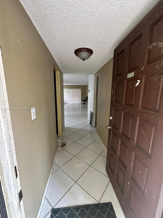 hallway featuring a textured ceiling and light tile patterned floors