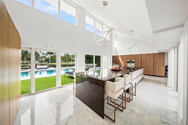 kitchen with a breakfast bar, a high ceiling, wood walls, and pendant lighting