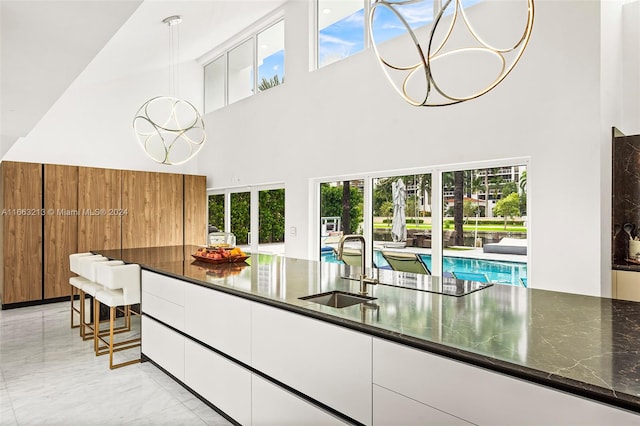 kitchen featuring white cabinets, a towering ceiling, sink, and a healthy amount of sunlight