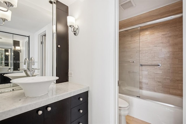 full bathroom with wood-type flooring, combined bath / shower with glass door, vanity, and toilet