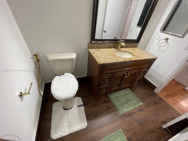 bathroom featuring wood-type flooring, vanity, and toilet