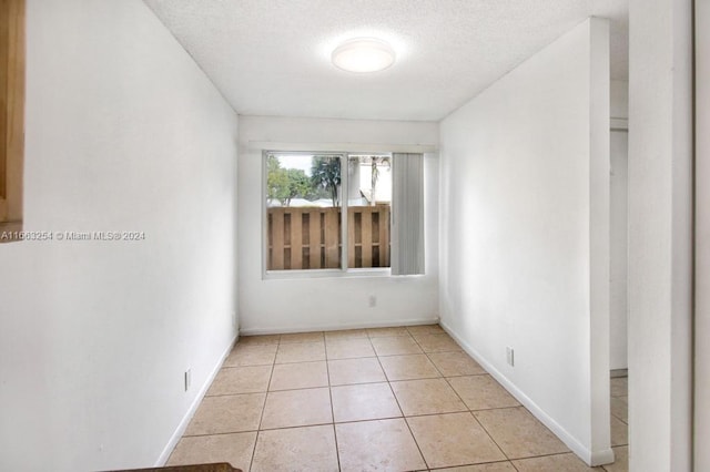 tiled empty room with a textured ceiling