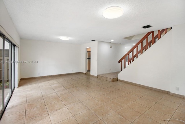 unfurnished living room with a textured ceiling and light tile patterned flooring