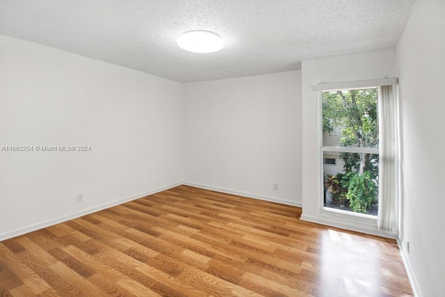 unfurnished room featuring light wood-type flooring and a textured ceiling