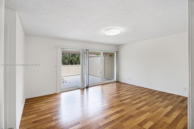 empty room with wood-type flooring and a textured ceiling