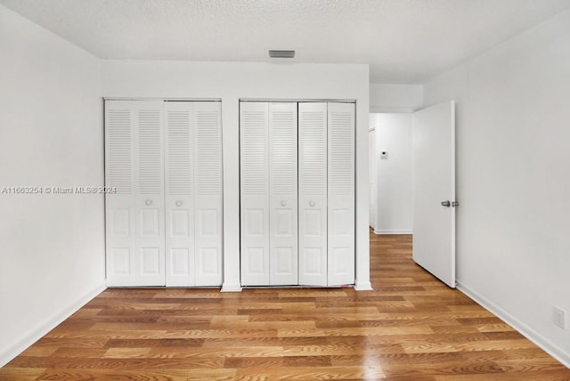 unfurnished bedroom with two closets and hardwood / wood-style flooring