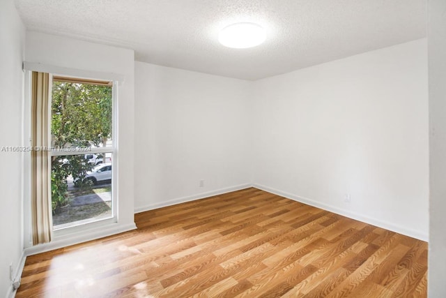 spare room featuring light hardwood / wood-style flooring and a textured ceiling