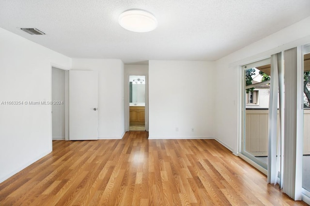 spare room featuring light wood-type flooring and a textured ceiling