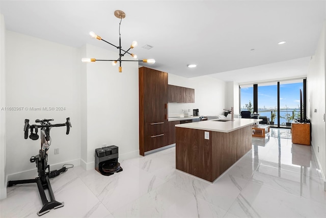 kitchen with a kitchen island, sink, dark brown cabinetry, pendant lighting, and an inviting chandelier