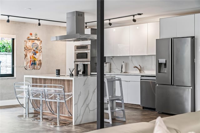 kitchen featuring rail lighting, stainless steel appliances, white cabinets, and extractor fan