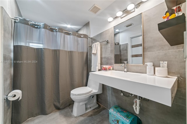 bathroom with walk in shower, tile walls, toilet, and concrete flooring