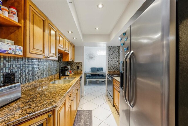 kitchen featuring dark stone counters, sink, stainless steel appliances, backsplash, and light tile patterned floors