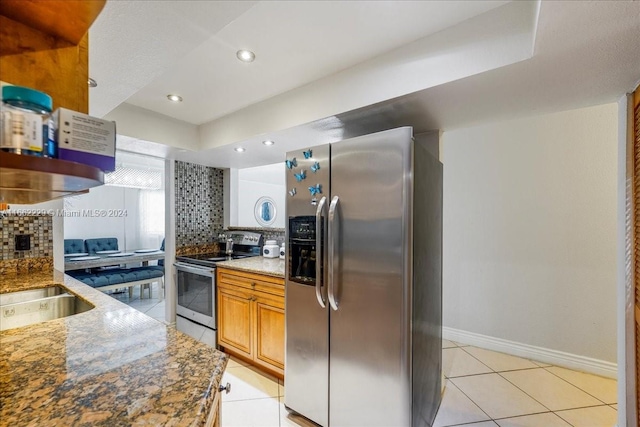 kitchen featuring light tile patterned flooring, stainless steel appliances, stone countertops, and decorative backsplash