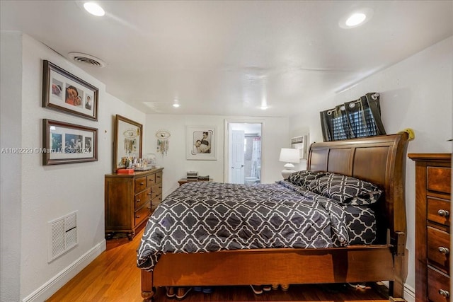 bedroom with hardwood / wood-style flooring and ensuite bath