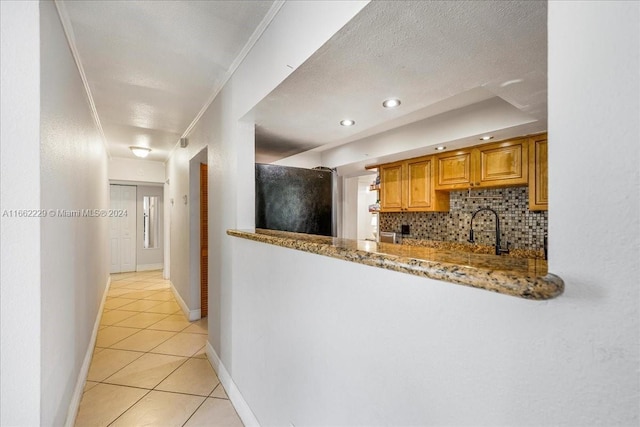 kitchen with light stone counters, black fridge, decorative backsplash, light tile patterned floors, and crown molding