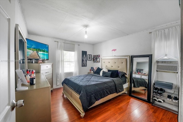 bedroom with a textured ceiling, ornamental molding, and hardwood / wood-style flooring