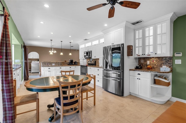 kitchen with appliances with stainless steel finishes, dark stone counters, pendant lighting, and white cabinets