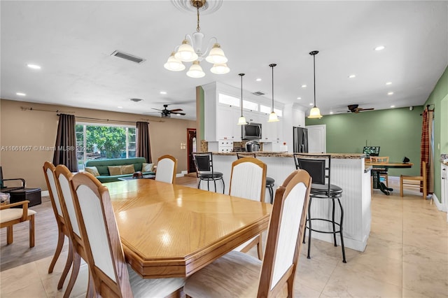 dining space with ceiling fan with notable chandelier and light tile patterned flooring