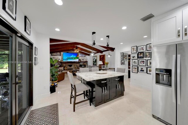 7706 SW 74th Ln, Miami, FL 33143 - kitchen with stainless steel fridge with ice dispenser, light stone countertops, white cabinets, visible vents, and a center island