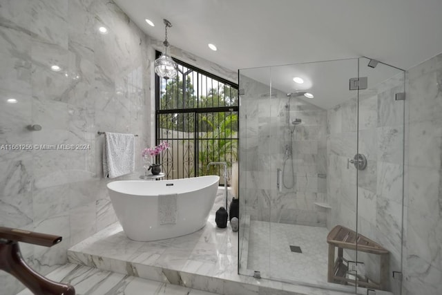 bathroom with shower with separate bathtub and tile walls