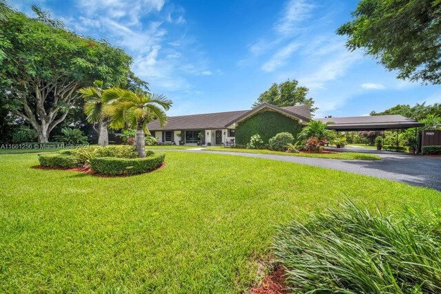 7706 SW 74th Ln, Miami, FL 33143 - view of front facade with a carport, driveway, stucco siding, and a front lawn