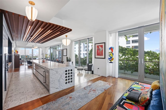 kitchen featuring light stone counters, a wall of windows, decorative light fixtures, and light hardwood / wood-style floors